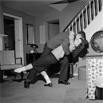 1960s TEENAGE COUPLE BOY & GIRL DANCING IN HOME LIVING ROOM DOING A BACKWARD DIP DANCE STEP