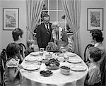 1970s THREE GENERATION FAMILY AROUND DINING ROOM TABLE WITH GRANDMOTHER SERVING A HAM