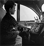 1940s BOY SITTING AT CONTROLS OF MOTOR YACHT WITH FATHER