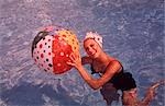 1960s WOMAN IN SWIMMING POOL HOLDING BEACH BALL