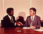 1970s AFRICAN AMERICAN MAN SHAKING HANDS WITH BANK LOAN OFFICER