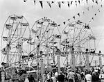 1950s FAIR SCENE SHOWING 2 GIANT FERRIS WHEELS & CROWD BELOW