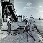 1930s LITTLE BOY WATCHING FISHERMAN UNLOADING LOBSTERS FROM NET ON DOCK IN NEW HARBOR LANDING MAINE