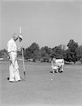 1930s 1940s 2 ELDERLY MEN ON GOLF GREEN ONE HOLDS FLAG AND THE OTHER KNEELS LINING UP HIS PUTT
