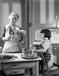 1920s GRANDMOTHER AND GRANDDAUGHTER IN KITCHEN PREPARING A CRUST FOR A CHERRY PIE