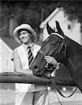 1930s WOMAN IN HAT SMILING LOOKING ASIDE WEARING STRIPED TIE HOLDING REINS AND HORSES HEAD SNAFFLE HUNTER BRIDLE