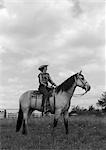 1950s WOMAN COWGIRL ON HORSE AT RANCH SMILING PROFILE OUTDOOR