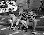 1970s THREE BORED BOYS SITTING ON CURB ALL WEARING STRIPED TEE SHIRTS SHORTS AND SNEAKERS