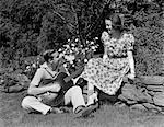 1940s YOUNG TEEN COUPLE BOY SITTING IN GRASS PLAYING GUITAR SERENADING GIRL SITTING ON STONE FENCE