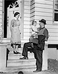 1940s FATHER ON STEPS HOLDING DAUGHTER WITH MOTHER WATCHING