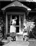 1930s MOTHER & DAUGHTER SWEEPING LEAVES FROM SIDEWALK IN FRONT OF HOUSE