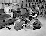 1960s FAMILY OF 5 LIVING ROOM MOTHER ON COUCH FATHER IN CHAIR WATCH KIDS 2 GIRLS AND 1 BOY PLAYING BOARD GAME ON FLOOR