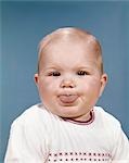 1960s PORTRAIT OF CUTE BLOND CHUBBY BABY STICKING OUT TONGUE