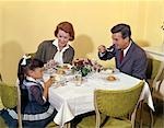 1960s FAMILY ENJOYING DINNER TOGETHER AT TABLE INDOOR MAN WOMAN GIRL