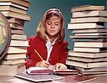 1960s TEENAGED GIRL WITH BOOKS STACKED ON BOTH SIDES OF HER AND GLOBE WRITING IN NOTEBOOK
