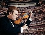 1960s MAN PLAYING THE VIOLIN IN CONCERT HALL