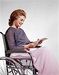 1960s SMILING WOMAN SITTING IN WHEELCHAIR READING INSURANCE CHECK