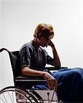 1960s SAD YOUNG WOMAN SITTING IN WHEELCHAIR BLANKET WRAPPED AROUND LEGS