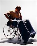 1960s SAD MAN SITTING IN WHEELCHAIR BLANKET WRAPPED AROUND LEGS LEANING CHIN ON HAND