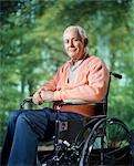 1970s SMILING SENIOR MAN SITTING IN WHEELCHAIR OUTDOORS