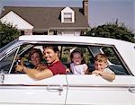 1960s SMILING SUBURBAN FATHER AND MOTHER WITH SON AND DAUGHTER SITTING IN WHITE FOUR DOOR SEDAN AUTOMOBILE