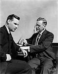 1930s MAN DOCTOR TAKING PULSE OF MAN PATIENT