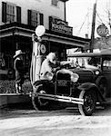 ELDERLY GRANDFATHER FILLING UP FORD CAR IN FRONT OF PENNSYLVANIA GENERAL STORE WITH GRANDSON WATCHING 1930s