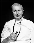 1950s MEDICAL DOCTOR HOLDING TIP OF STETHOSCOPE IN RIGHT HAND