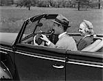 DATE DES ANNÉES 1940 COUPLE VOLANT VOITURE DÉCAPOTABLE