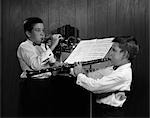 1960s PAIR OF BOYS AT MUSIC STAND WEARING WHITE SHIRTS & BOWTIES ONE PLAYING TRUMPET & ONE PLAYING CLARINET