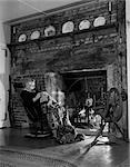 1950s ELDERLY WOMAN IN ROCKER IN FRONT OF FIREPLACE DOING NEEDLEWORK