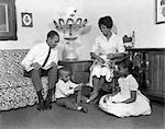 1960s SMILING AFRICAN AMERICAN FAMILY FATHER MOTHER DAUGHTER SON SITTING TOGETHER IN LIVING ROOM