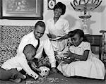 1960s AFRICAN AMERICAN FAMILY ON LIVING ROOM FLOOR COUNTING CHANGE IN PIGGY BANK