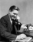 1930s BUSINESS MAN ON TELEPHONE IN OFFICE WRITING