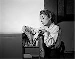 1950s WOMAN WORKING IN OFFICE LOOKING THROUGH FILES IN FILE CABINET