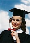 1940s 1950s SMILING FEMALE GRADUATE HOLDING DIPLOMA WRAPPED IN RED RIBBON