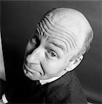 CHARACTER BALD MAN LOOKING UP TO CAMERA AMUSED WORRIED FUNNY FACE EXPRESSION WRINKLED BROW SHOT FROM ABOVE