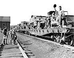 1940s WORLD WAR II FREIGHT TRAIN OF JEEPS AND HALF TRACKS ON WAY TO THE FRONT FACTORY WORKERS BID FAREWELL TO SOLDIERS ON TRAIN