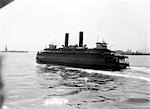 1930s NEW YORK CITY HARBOR FERRY BOAT WITH TWO SMOKE STACKS VIEWED FROM THE STERN STATUE OF LIBERTY ON HORIZON