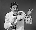 1950s 1960s MAN WHITE TUXEDO JACKET HOLD MICROPHONE SING TALK GESTURE WITH HAND PERFORMER HOST EMCEE