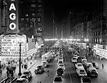 1950s 1953 NIGHT SCENE OF CHICAGO STATE STREET WITH TRAFFIC AND MOVIE MARQUEE WITH PEDESTRIANS ON THE SIDEWALKS