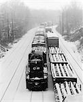 1970s PAIR OF FREIGHT TRAINS TRAVELING DOWN SNOWY TRACKS