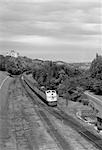 1950s OVERHEAD VIEW OF STREAMLINED DIESEL LOCOMOTIVE PASSENGER RAILROAD TRAIN PASSING THROUGH SUBURBAN