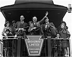 1930s GROUP FAMILY MEN WOMEN CHILDREN ON PLATFORM OF CABOOSE OF TRAIN SENIOR MAN WAVING