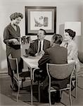 1950s CARD PARTY OF 2 COUPLES WITH WOMAN SERVING DRINKS