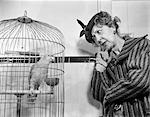 1940s FUNNY WOMAN IN HAT & COAT TALKING TO PARROT IN BIRD CAGE