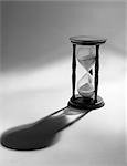 STILL LIFE OF HOURGLASS WITH SAND HALFWAY DOWN CASTING SHADOW