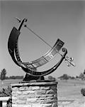 SUNDIAL STONE PEDESTAL METAL BAR ROMAN NUMERALS SHADOW CREATED BY METAL BOW & ARROW SUN SOLAR TIME DAY OUTDOORS HOURS MINUTES