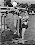 1940s GIRL AND BOY STANDING IN POOL WEARING BATHING SUITS