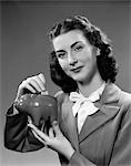 1940s WOMAN PUTTING CHANGE INTO PIGGY BANK